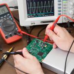 Engineer's hands with the probes testing voltage on the plate